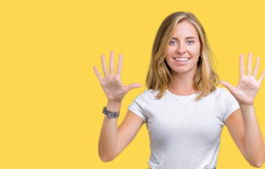 Gösterilen ve parmakları ile işaret izole arka plan üzerinde rahat beyaz t-shirt giyen güzel genç kadın kendinden emin ve mutlu gülümseyerek süre on numara.