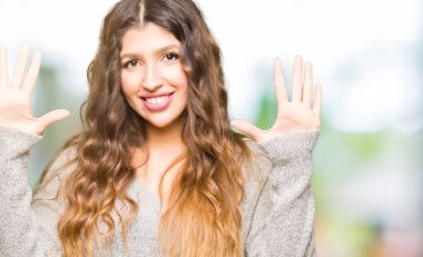 Gösterilen ve parmak sayısı on kendinden emin ve mutlu gülümseyerek süre ile yukarıyı Kış elbise giyen genç güzel kadın.