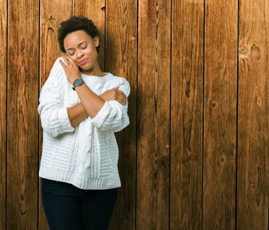 Güzel genç Afro-Amerikan kadın giyiyor kazak izole üzerinde emin gülümseyen Hugging kendini mutlu ve olumlu, arka plan. Kendi aşk ve öz bakım