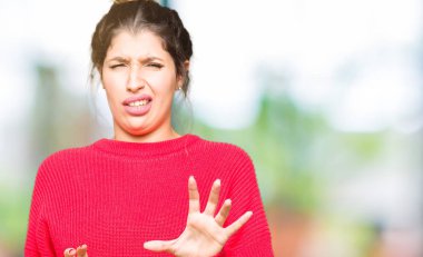 Kırmızı kazak ve çörek giyen genç güzel kadın tiksinti ifadesi, memnun ve korkulu tiksinti yüz yapıyorsun çünkü nefret tepki. Elleriyle kaldırdı. Sinir bozucu kavramı.