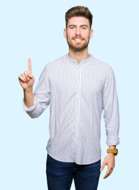 Genç ve yakışıklı bir numaralı parmağıyla kendini beğenmiş ve mutlu gülümserken..