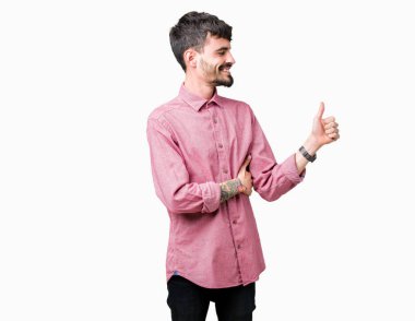 Yanına bir jest yapıyorsun gülümseyen izole arka plan gurur, seyir üzerinde pembe gömlek giymiş genç yakışıklı adam yaşasın