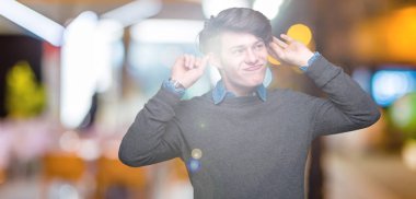 Genç yakışıklı zarif adam izole arka plan gülen çekerek kulakları ile parmak, komik jest. Seçmelere sorun