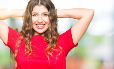 Rahat t-shirt dinlenirken ve germe giyen genç güzel kadın kollar ve eller baş ve boyun arkasında ile mutlu gülümseyerek