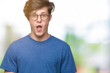 Korkuyor ve şok sürpriz ifade, korku ve heyecan yüz ile izole arka plan üzerinde gözlük takan genç yakışıklı adam.