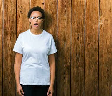 Güzel genç Afro-Amerikan kadın korkuyor ve şok sürpriz ifade, korku ve heyecan yüz ile izole arka plan üzerinde gözlük.