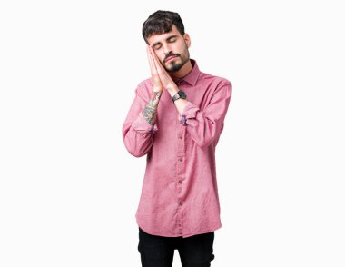 Uyku yorgun hayal ve ellerle birlikte poz ile kapalı gözler gülümseyen izole arka plan üzerinde pembe gömlek giymiş genç yakışıklı adam.
