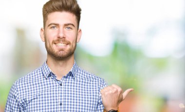 Genç yakışıklı Bussines adam mutlu yüz görünümlü ve başparmak yukarı ile yan işaret gülümseyen.