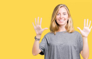 Gösterilen ve parmakları ile işaret izole arka plan üzerinde büyük boy rahat t-shirt giyen güzel genç kadın kendinden emin ve mutlu gülümseyerek süre on numara.