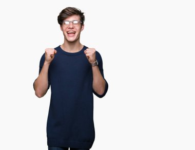 Yakışıklı delikanlı izole arka plan üzerinde kutluyor gözlük takan şaşırttı ve başarı için kaldırdı kollarını açarak hayret ve gözleri açık. Kazanan kavramı.