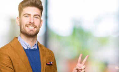 Mutlu yüz zafer işareti yaparken kameraya göz kırpıyor ile gülümseyen genç yakışıklı iş adamı. İki numaralı.