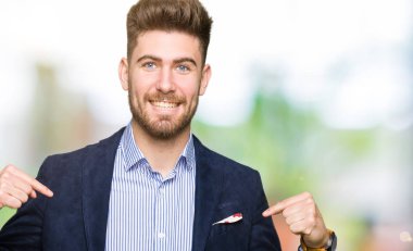 Yüzünde gülümseme ile kendinden emin görünüyorsun, kendini gururlu ve mutlu parmakları ile işaret genç yakışıklı bussines adam.