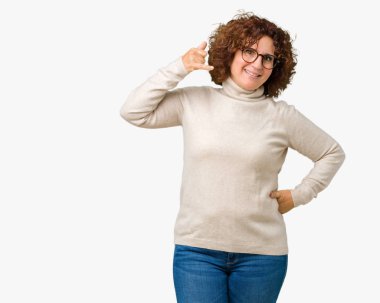 Boğazlı kazak ve gözlük yapıyor gülümseyen izole arka plan üzerinde giyen güzel orta ager üst düzey kadın telefon hareketi ile el ve parmak telefonda konuşuyor gibi. Kavramları iletişim.