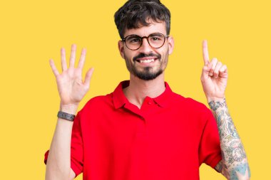 Gösterilen arka plan üzerinde gözlük takan genç yakışıklı adam izole ve parmakları ile işaret kendinden emin ve mutlu gülümseyerek süre 6 numara.