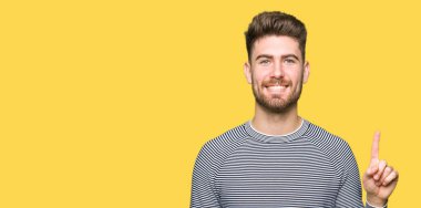 Gösterilen ve kendinden emin ve mutlu gülümseyen bir parmak ile işaret eden oktan yukarı kazak giyen genç yakışıklı adam çizgili.