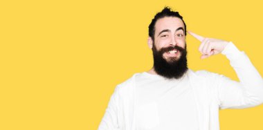 Genç hippi erkek uzun saç ve sakal bir parmak, harika bir fikir ile baş gösteren gülümseyen ya da düşünce sportif sweatshirt giyiyor, iyi hafıza ile