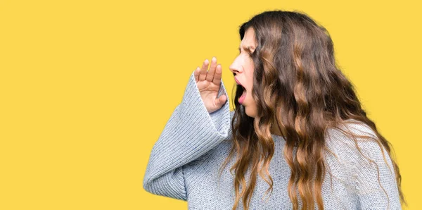 若い美しい女性は冬のセーターを着て大声で叫び 口の中で手で横に大声で叫ぶ コミュニケーションの概念 — ストック写真