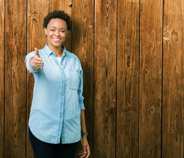 Genç güzel Afrikalı-Amerikalı kadın dostu sunan el sıkışma tebrik ve davet edici olarak gülümseyen izole arka plan yüzünden. Başarılı iş.