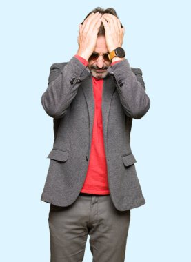 Orta yaş yakışıklı iş adamı güneş gözlüğü takan baş ağrısı umutsuz muzdarip ve stresli çünkü ağrı ve migren. Eller baş üstünde.