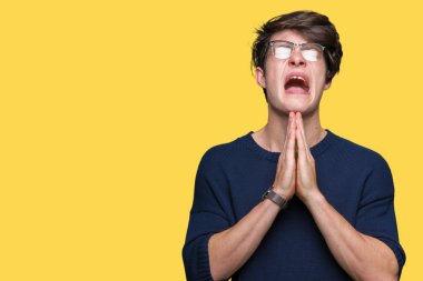 Yalvarıyor ve umut ifade yüzünde çok duygusal ve endişe ile birlikte elleriyle dua izole arka plan üzerinde gözlük takan yakışıklı delikanlı. Bağışlanmak. Din kavramı.