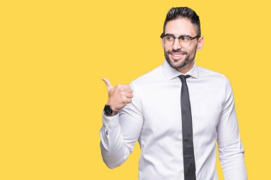 Seyir ve başparmak yanında yukarıyı mutlu yüz ile gülümseyen izole arka plan üzerinde gözlük takan genç yakışıklı iş adamı.