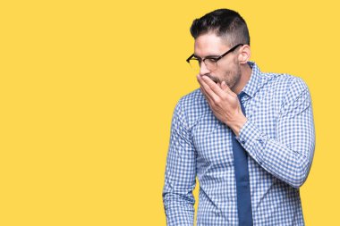 İzole arka plan üzerinde gözlüklü genç iş adamı esneme yorgun kapsayan ağız el ile sıkılmış. Restless ve uyku hali.