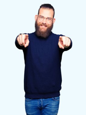 Gözlük ve balıkçı yakalı kazak giyen genç sarışın adam size ve parmaklar ile kamera Işaret, olumlu ve neşeli gülümseyen