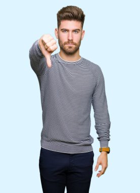 Mutsuz ve kızgın ret gösterilen ve başparmak aşağı hareketi ile negatif seyir çizgili süveter giymiş yakışıklı delikanlı. Kötü ifade.