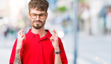 Umut ve gözleri kapalı geçiş parmaklarıyla gülümseyen izole arka plan üzerinde gözlük takan yakışıklı delikanlı. Şans ve batıl kavramı.