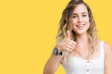 Izole arka plan üzerinde genç güzel sarışın kadın el ile jest kadar mutlu başparmak yapıyor. Başarı gösteren kameraya bakarak ifadeyi onaylama.