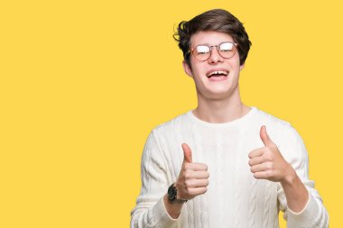 Yakışıklı delikanlı izole arka plan başarı işareti el ile pozitif jest yapıyor üzerinde gözlük takan başparmak gülümseyen ve mutlu. Neşeli bir ifadeyle, kazanan jest kameraya bakıyor.