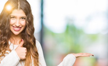 Beyaz kazak gösteren palm el giyen ve yukarıya, mutlu ve neşeli gülümseyen baş parmakları Tamam jest yapıyor genç güzel kadın