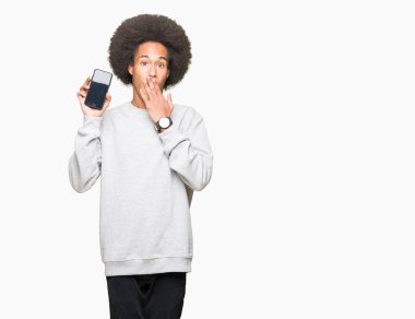 Afro saç ile genç Afrikalı Amerikalı adam akıllı telefon ekran kapağı ağız ile el hata için utanç ile şok, korku ifade, sessizlik, gizli kavramı korkuyor