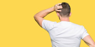 Yakışıklı adam geriye doğru elle kafasında şüphe hakkında düşünme casual beyaz t-shirt giyen