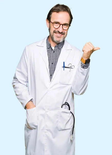 中年医生男子穿着医疗外套微笑与幸福的脸看着 并指着一边竖起大拇指 — 图库照片