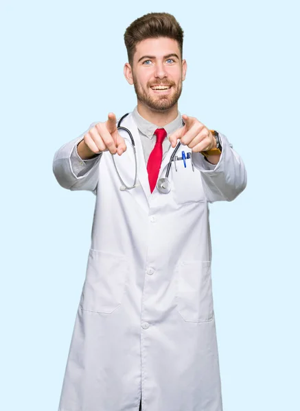 医療を着た若いハンサムな医者の男は 指でカメラにポインティングをコートし 肯定的な陽気な笑顔 — ストック写真