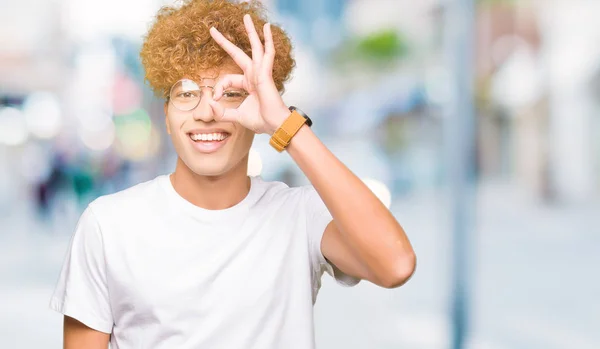 年轻英俊的男人与非洲头发戴眼镜做确定的手势与手微笑 眼睛通过手指看着快乐的脸 — 图库照片