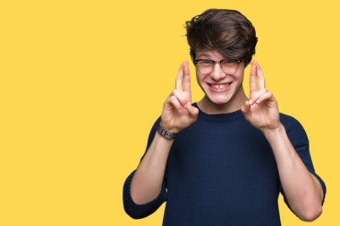 Umut ve gözleri kapalı geçiş parmaklarıyla gülümseyen izole arka plan üzerinde gözlük takan yakışıklı delikanlı. Şans ve batıl kavramı.