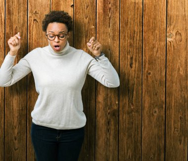 Genç güzel Afrikalı-Amerikalı kadın gözlük izole üzerinde işaretleme aşağı reklam, sürpriz yüz ve açık ağız gösterilen parmakları ile arka plan