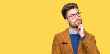 Gözlüklü el ile çene düşünme hakkında soru, dalgın ifade üzerine genç yakışıklı iş adamı. Düşünceli yüzüyle gülümsüyor. Şüphe kavramı.