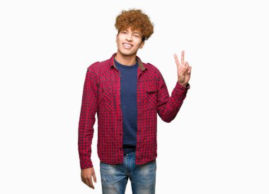 Afro saçlı Genç yakışıklı öğrenci adam zafer işareti yapıyor kamera mutlu yüz göz kırpıyor ile gülümseyen bir ceket giyiyor. İki numara.