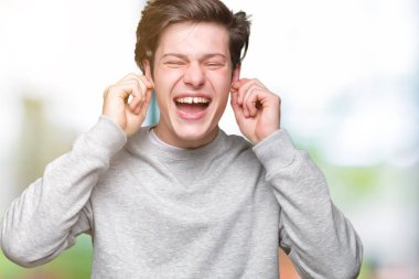 Yüksek sesle müzik gürültü rahatsız ifade parmaklarıyla kulaklarıyla kapsayan izole arka plan üzerinde sweatshirt giyen genç yakışıklı sportif adam. Sağır kavramı.
