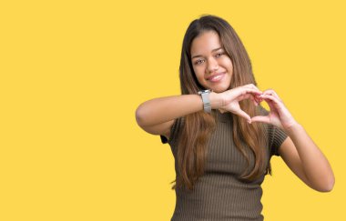 Genç güzel esmer kadın kalp simgesi ve elleriyle şekil gösterilen aşık gülümseyen izole arka plan yüzünden. Romantik kavramı.