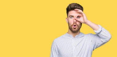 Yakışıklı genç adam şaşırmış yüz ifadesiyle, parmaklarının arasından bakarak iyi bir hareket yapıyor. İnançsız ifade.