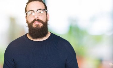 Uzun saç ve sakal gevşek ciddi ifade ile yüzünde gözlüklü genç hipster adam. Basit ve doğal kameraya bakıyor.