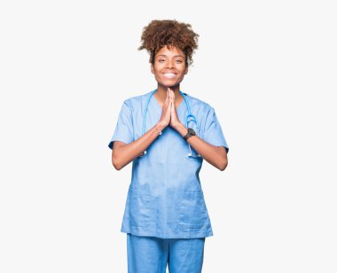 İzole arka plan birlikte AF emin gülümseyen için soran ellerle dua genç Afro-Amerikan doktor kadın.