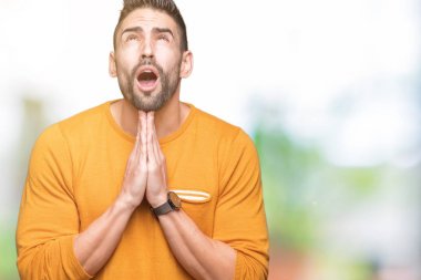 Yakışıklı delikanlı yalvarıyor ve umut ifade yüzünde çok duygusal ve endişe ile birlikte elleriyle dua izole arka plan üzerinde. Bağışlanmak. Din kavramı.