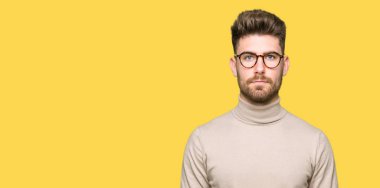 Gevşek ciddi ifade ile yüzünde gözlüklü genç yakışıklı iş adamı. Basit ve doğal kameraya bakıyor.