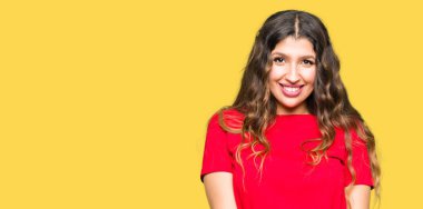 Rahat t-shirt eller birlikte giyen genç güzel kadın ve parmakları rahat ve neşeli gülümseyen geçti. Başarı ve iyimser