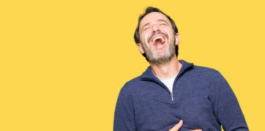 Bir kazak giyen orta çağ yakışıklı adam gülümsüyor ve sert yüksek sesle gülüyor Çünkü komik çılgın şaka. Mutlu ifade.